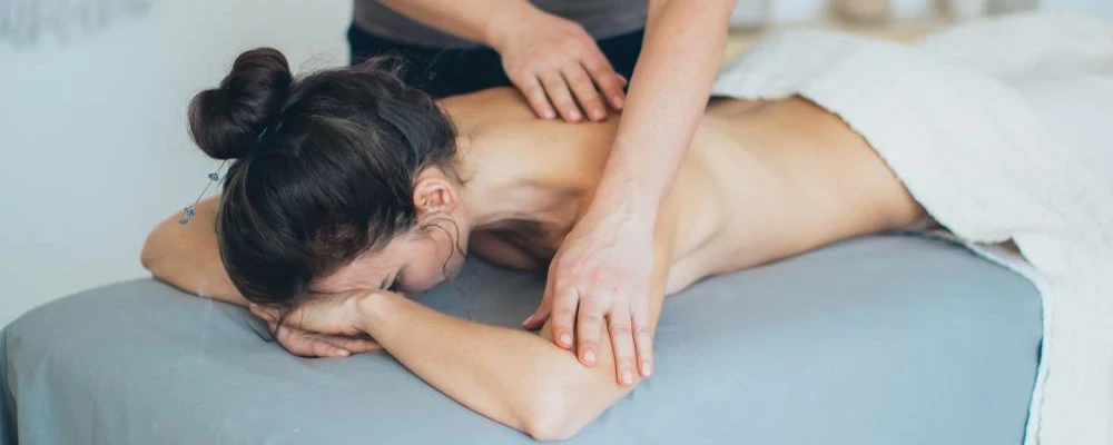 A woman receiving massage therapy that is covered by Medicare.